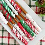 chocolate covered Christmas pretzel rods with sprinkles on white platter