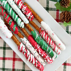 chocolate covered Christmas pretzel rods with sprinkles on white platter
