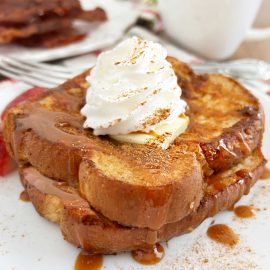 eggnog french toast with whipped cream and syrup on plate