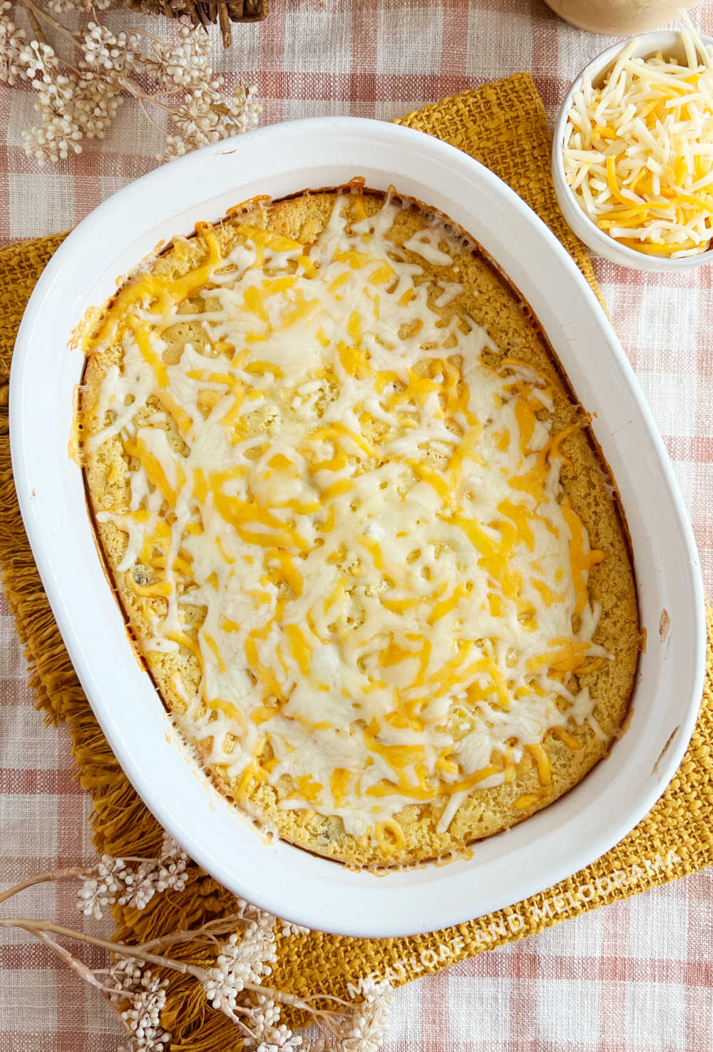 baked jiffy corn casserole topped with shredded cheese on holiday table
