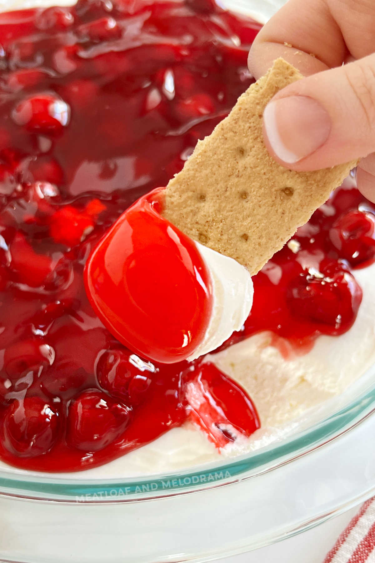 cherry cheesecake dip with cherry pie filling on a graham cracker