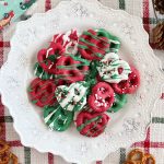 white chocolate dipped christmas pretzels on a snowflake plate