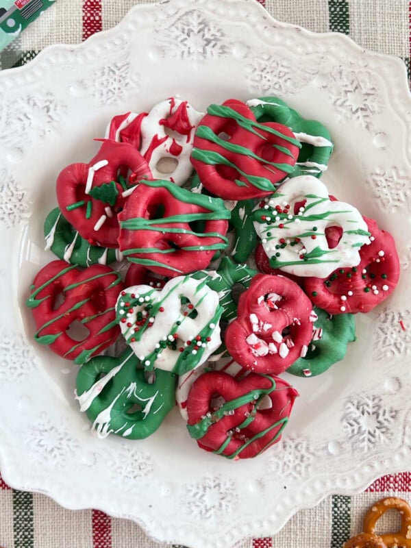 white chocolate dipped christmas pretzels on a snowflake plate