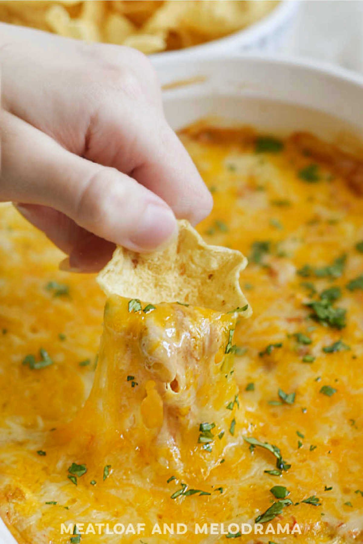 bean dip with gooey cheddar cheese pull on tortilla chip