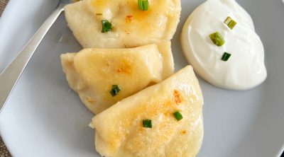 homemade potato cheese pierogi on plate with sour cream
