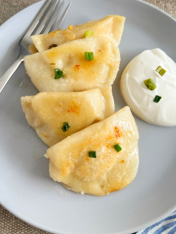 homemade potato cheese pierogi on plate with sour cream