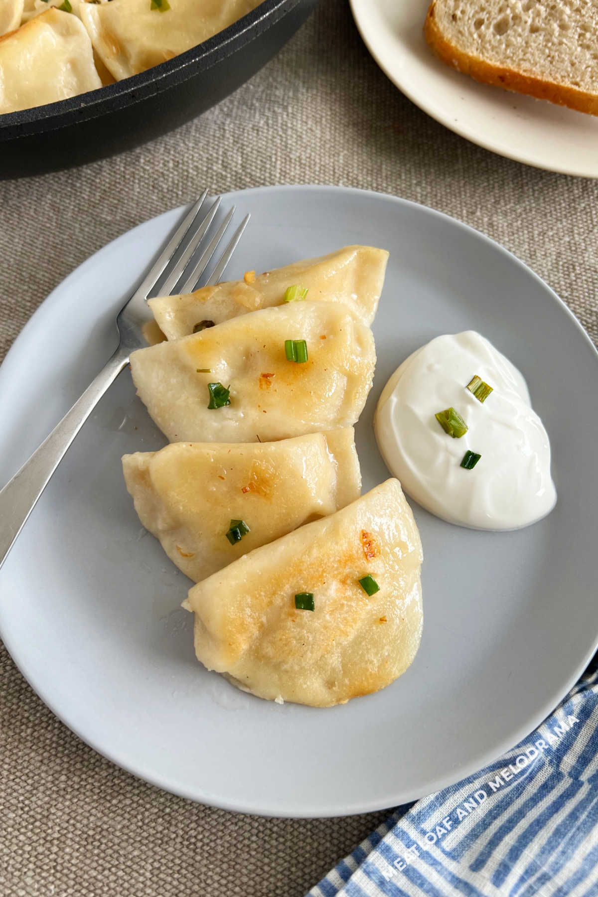 potato cheese pierogi with onions and sour cream on plate