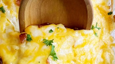 crack chicken casserole recipe with cheddar cheese and bacon on a serving spoon