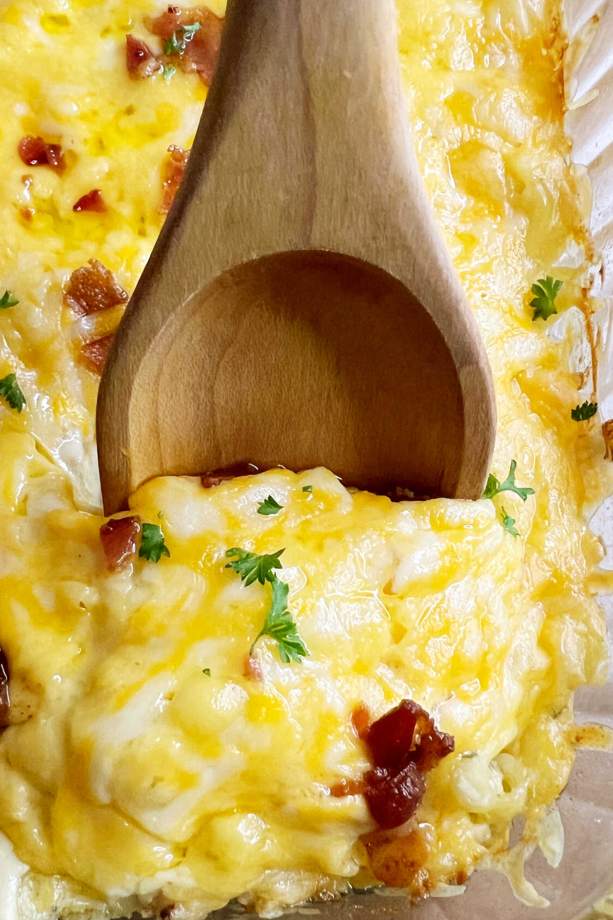 crack chicken casserole with melted cheese and bacon on a serving spoon