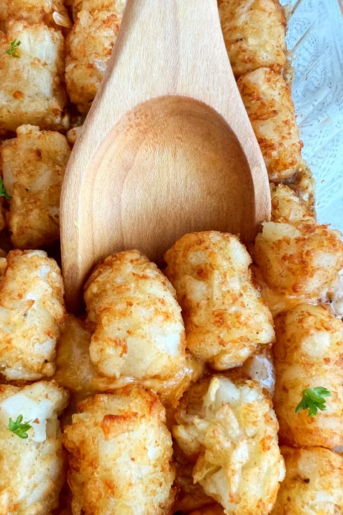 cheesy tater tot casserole on wooden serving spoon
