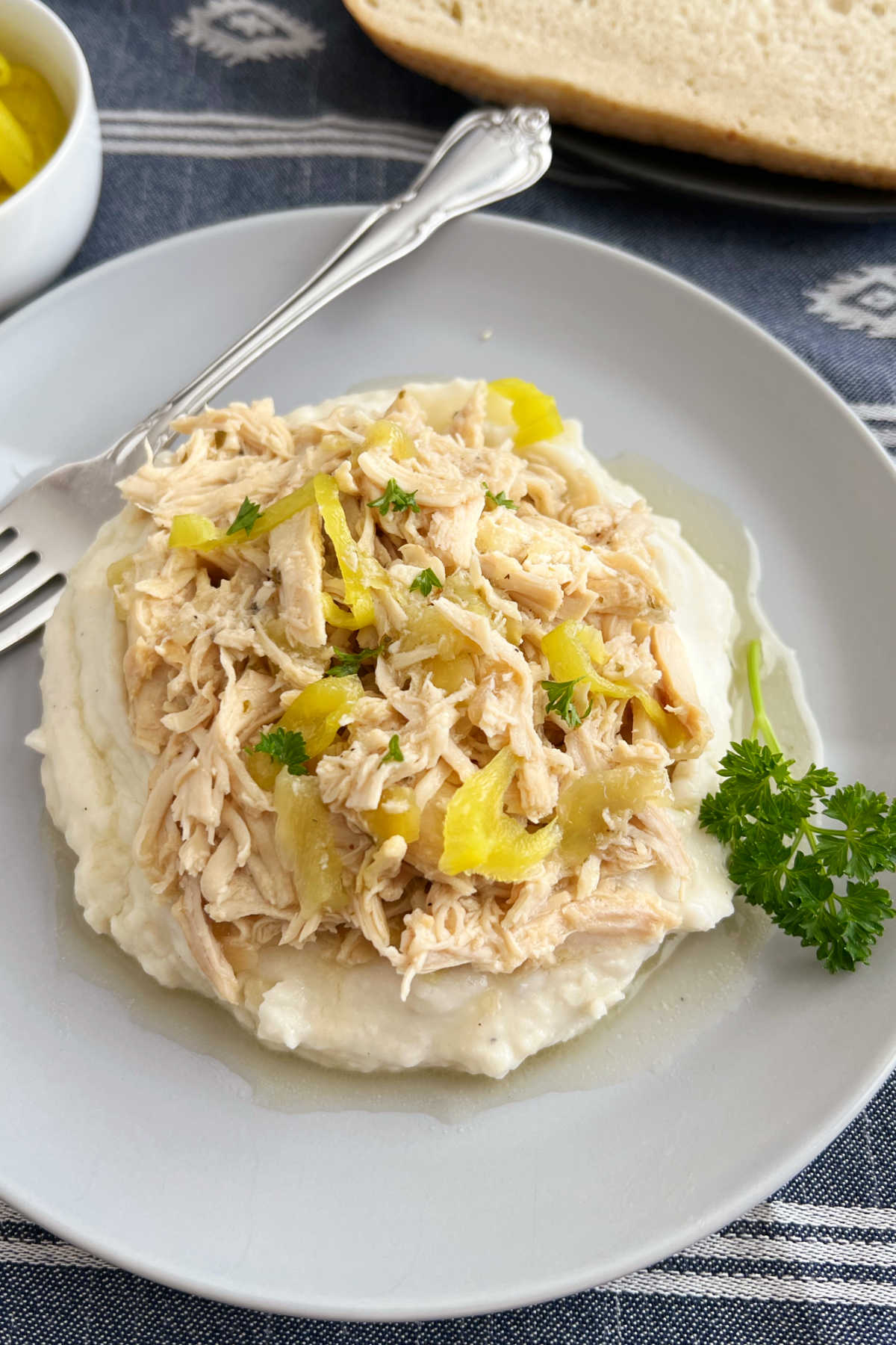 crock pot Mississippi chicken with pepperoncini peppers over mashed potatoes on a plate