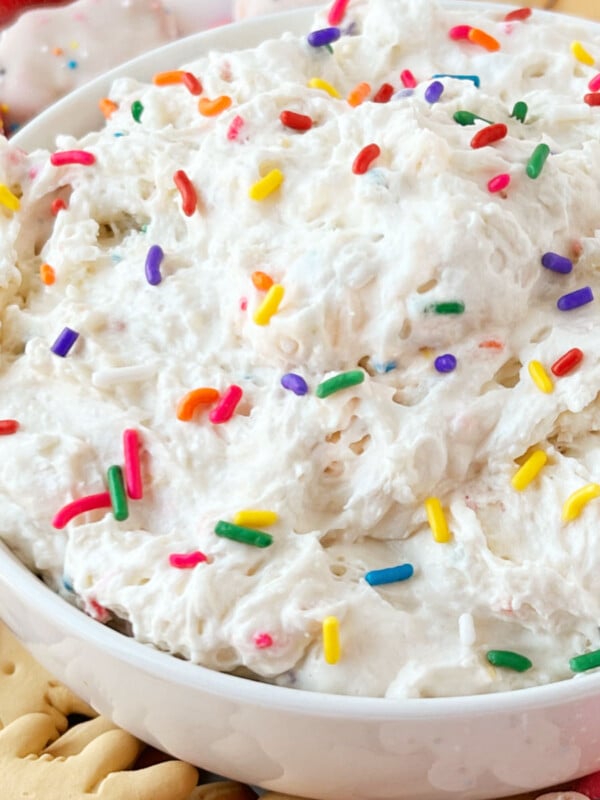 dunkaroo dip (funfetti cake batter dip) in a serving bowl with animal crackers and rainbow sprinkles on top
