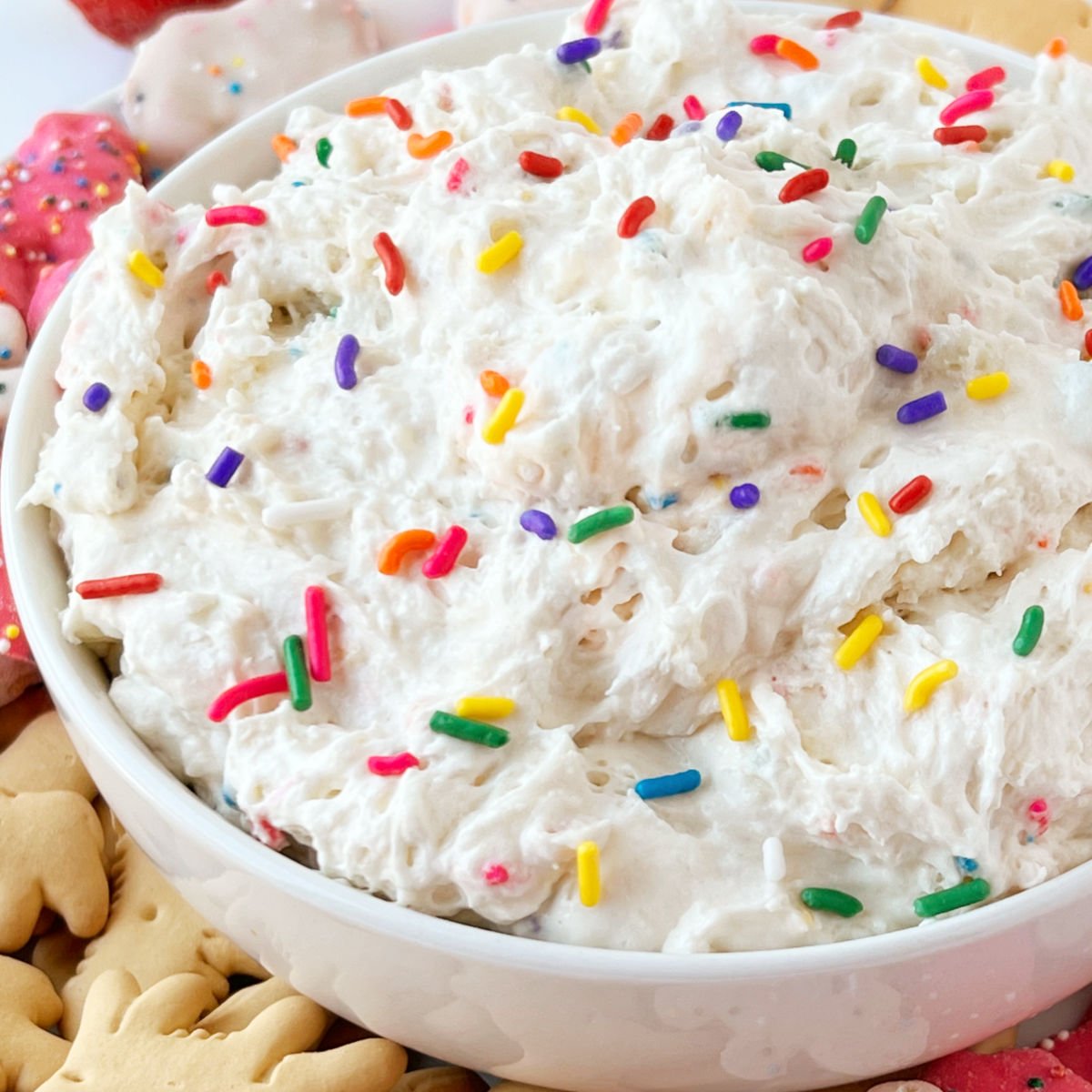 dunkaroo dip (funfetti cake batter dip) in a serving bowl with animal crackers and rainbow sprinkles on top