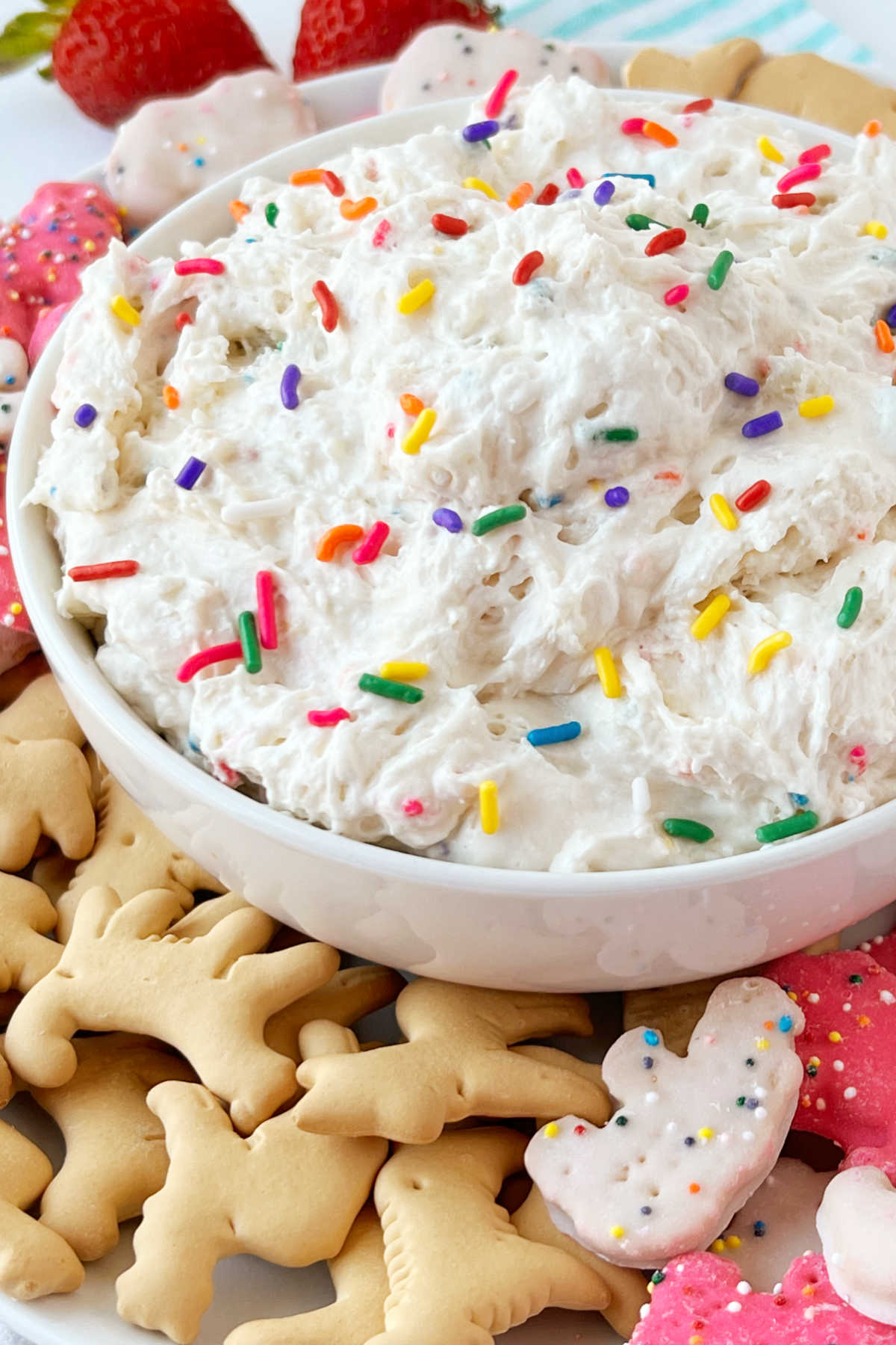 Dunkaroo dip (funfetti cake batter dip) with rainbow sprinkles in a serving bowl with animal crackers and circus crackers