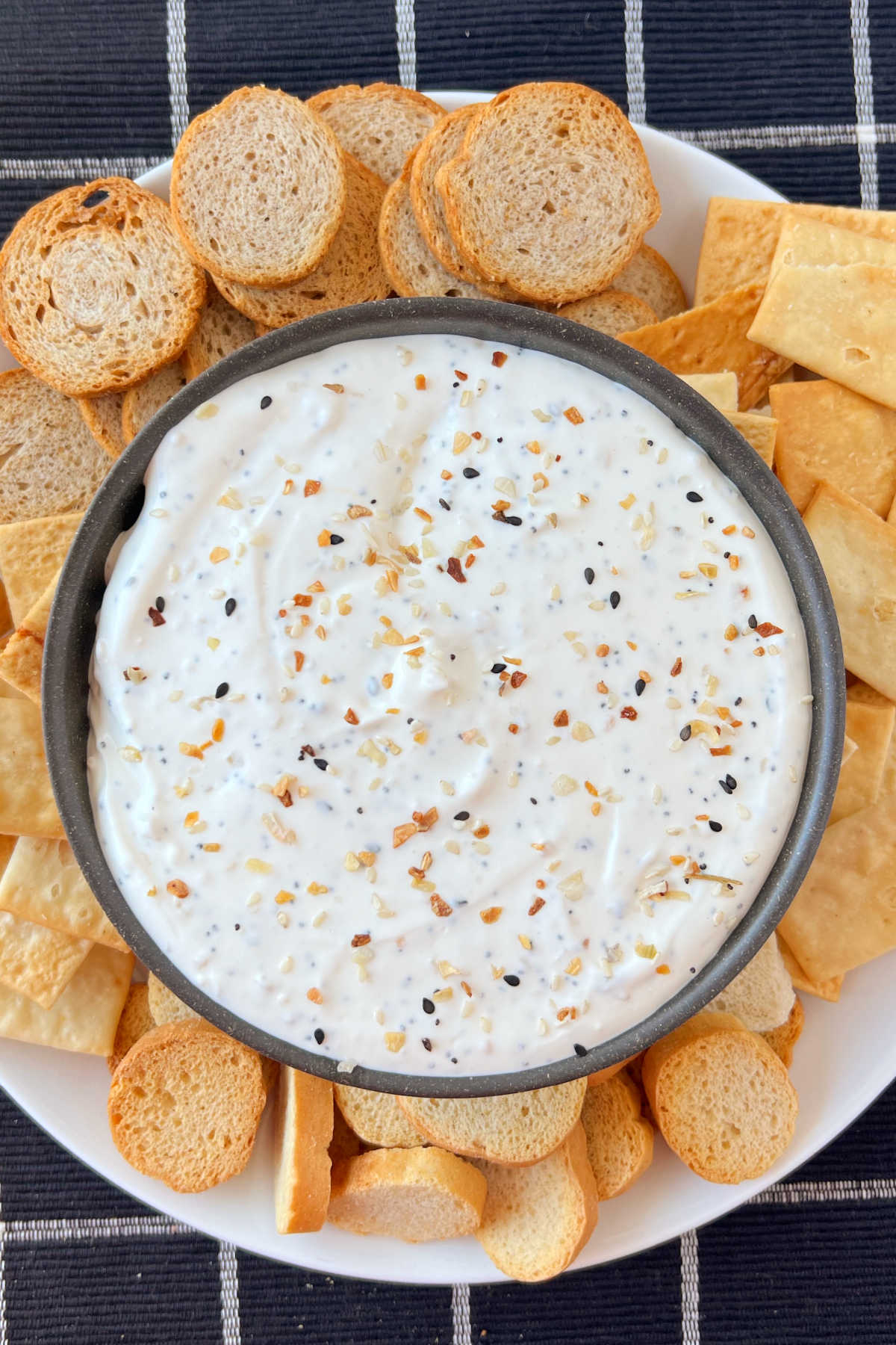 bowl of everything bagel dip on platter with bagel chips and dippers
