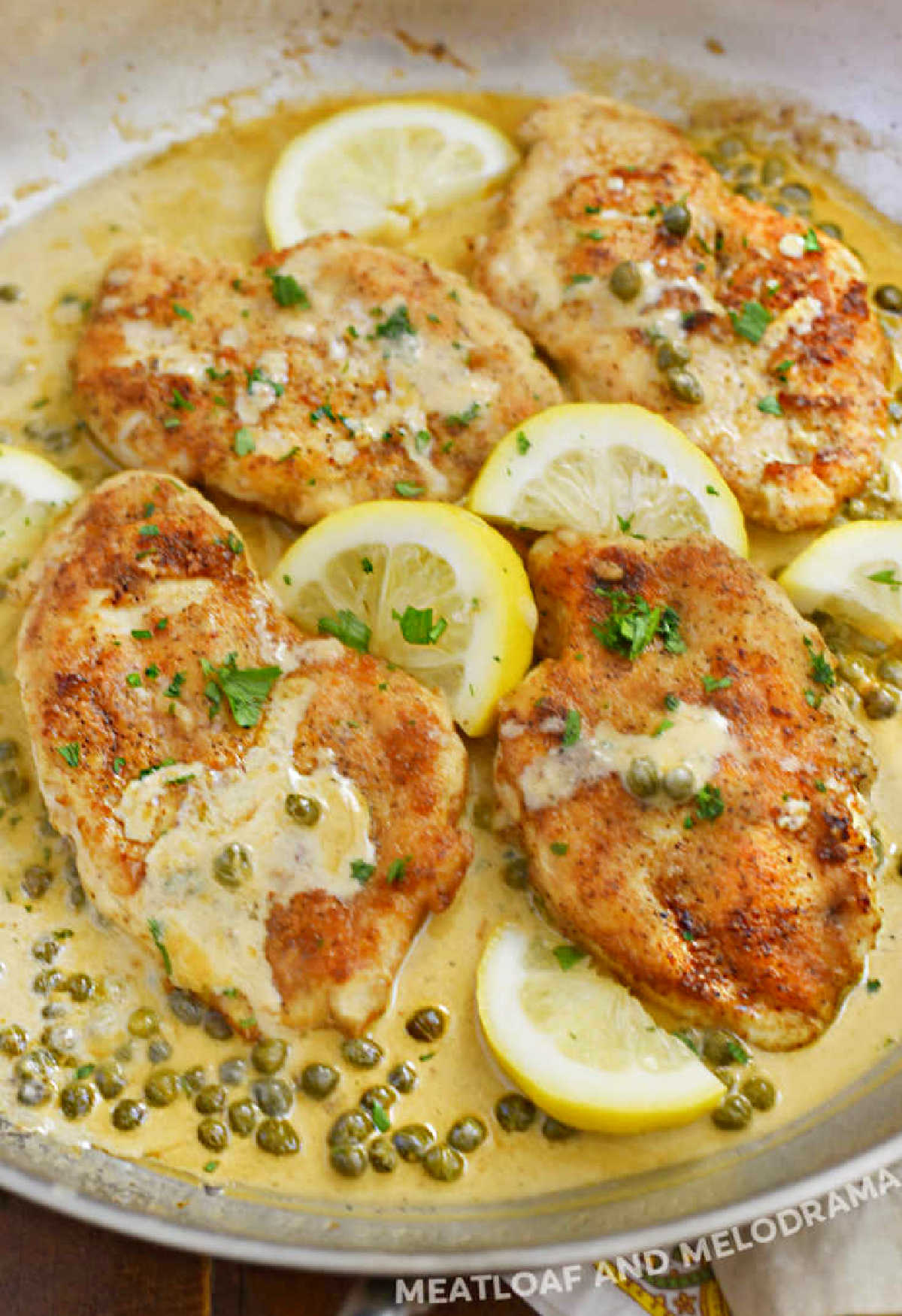 lemon chicken piccata in creamy lemon butter sauce with white wine and capers in skillet