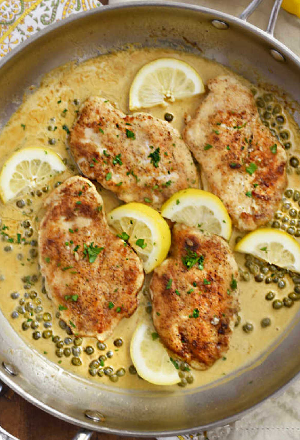 chicken piccata in skillet with capers and lemon slices