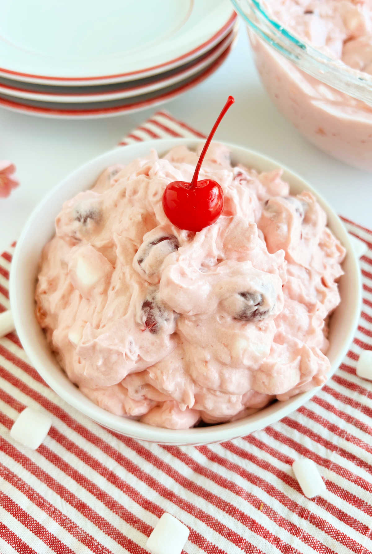 cherry fluff salad with cool whip and vanilla pudding in a bowl with maraschino cherry on top