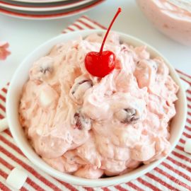 cherry fluff salad with maraschino cherry in a white bowl
