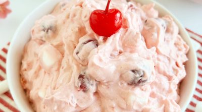 cherry fluff salad with maraschino cherry in a white bowl