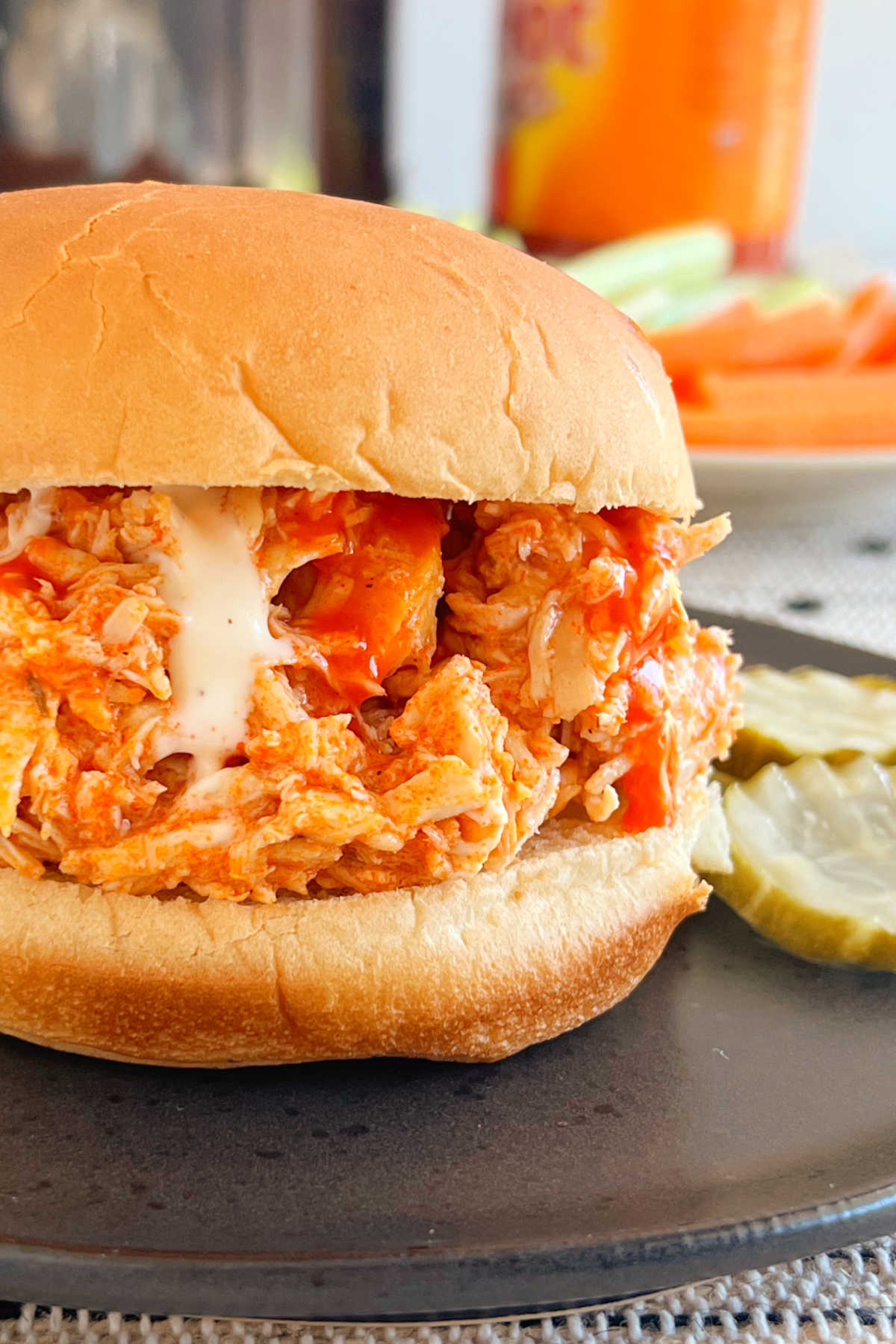 pulled crock pot buffalo chicken sandwich with ranch dressing on plate