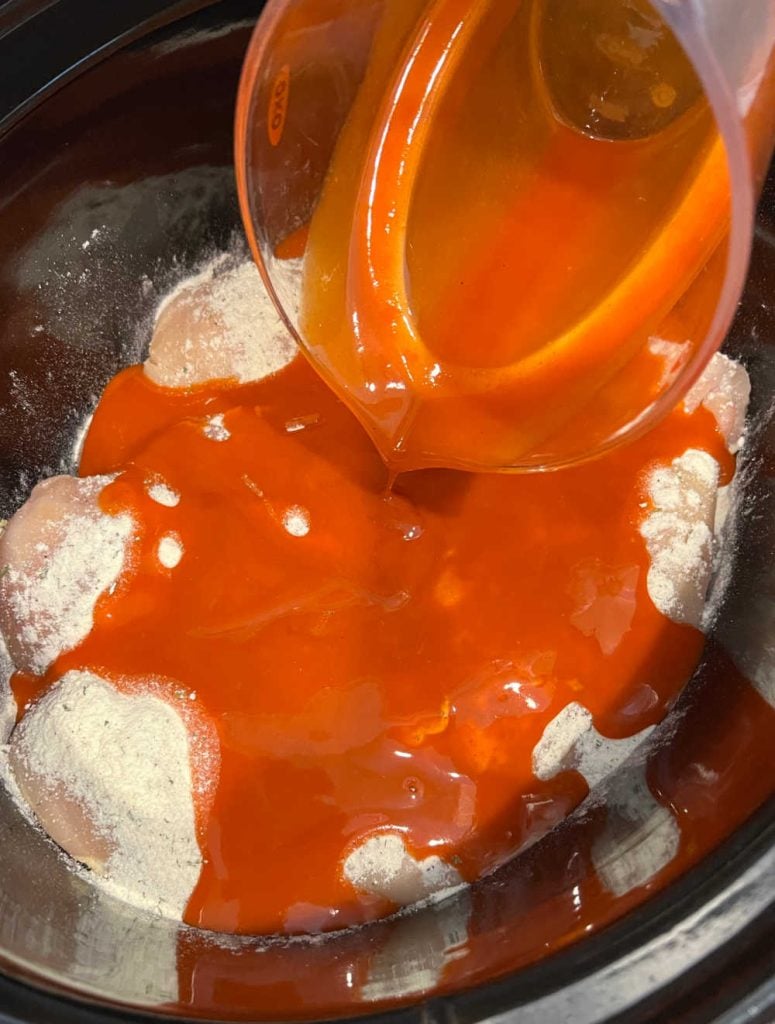 pour buffalo sauce over chicken in slow cooker