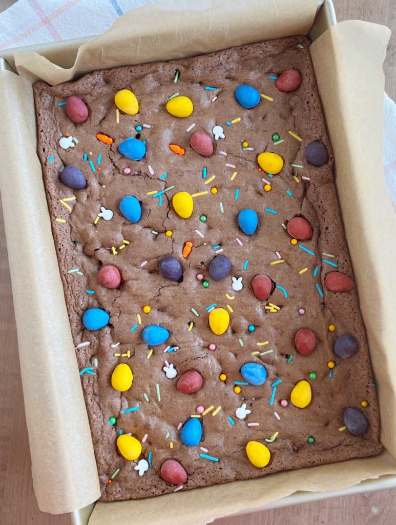 fudgy brownies topped with mini eggs and seasonal sprinkles in baking dish