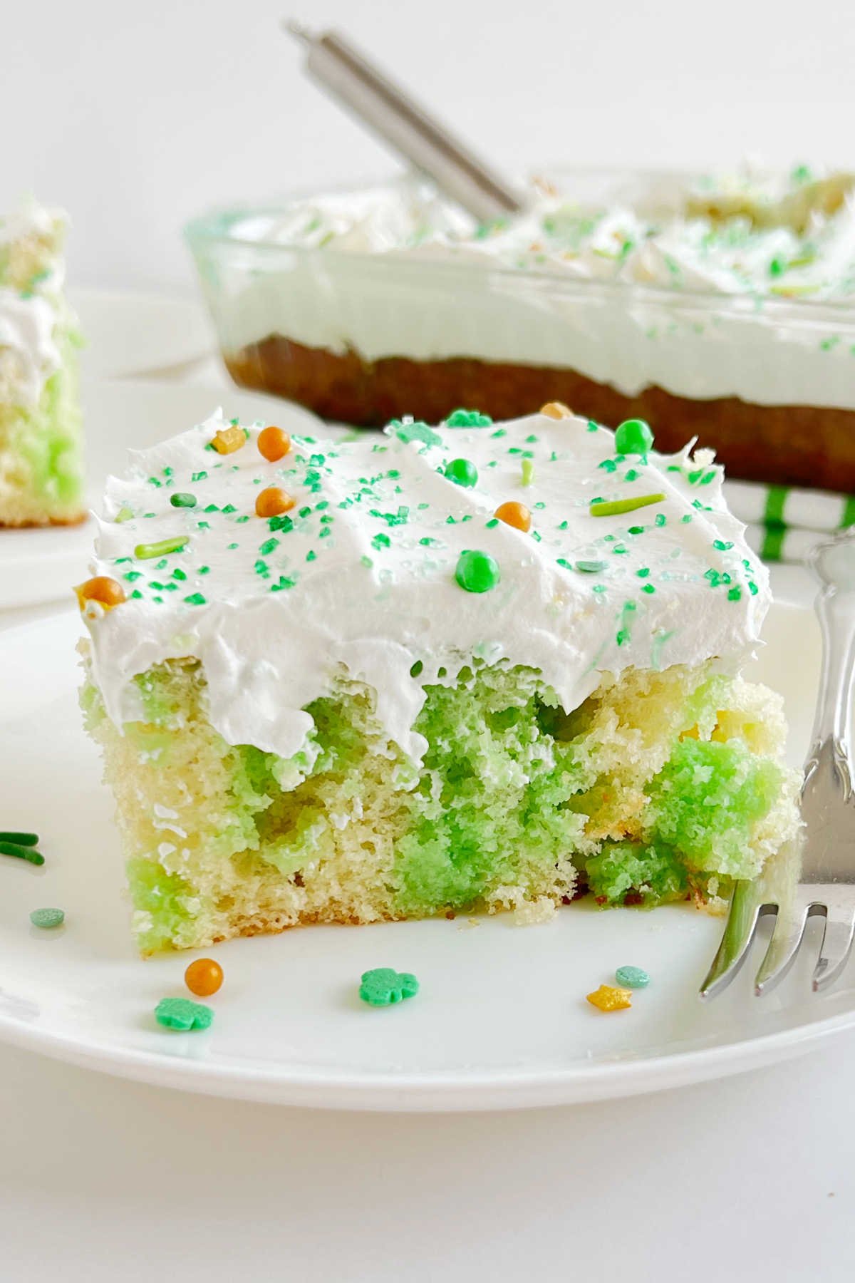 slice of lime jello poke cake with cool whip topping on plate