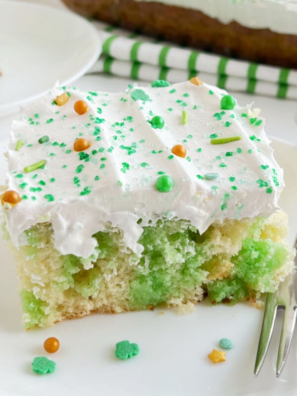 lime jello poke cake with St. Patrick's Day sprinkles on a white plate