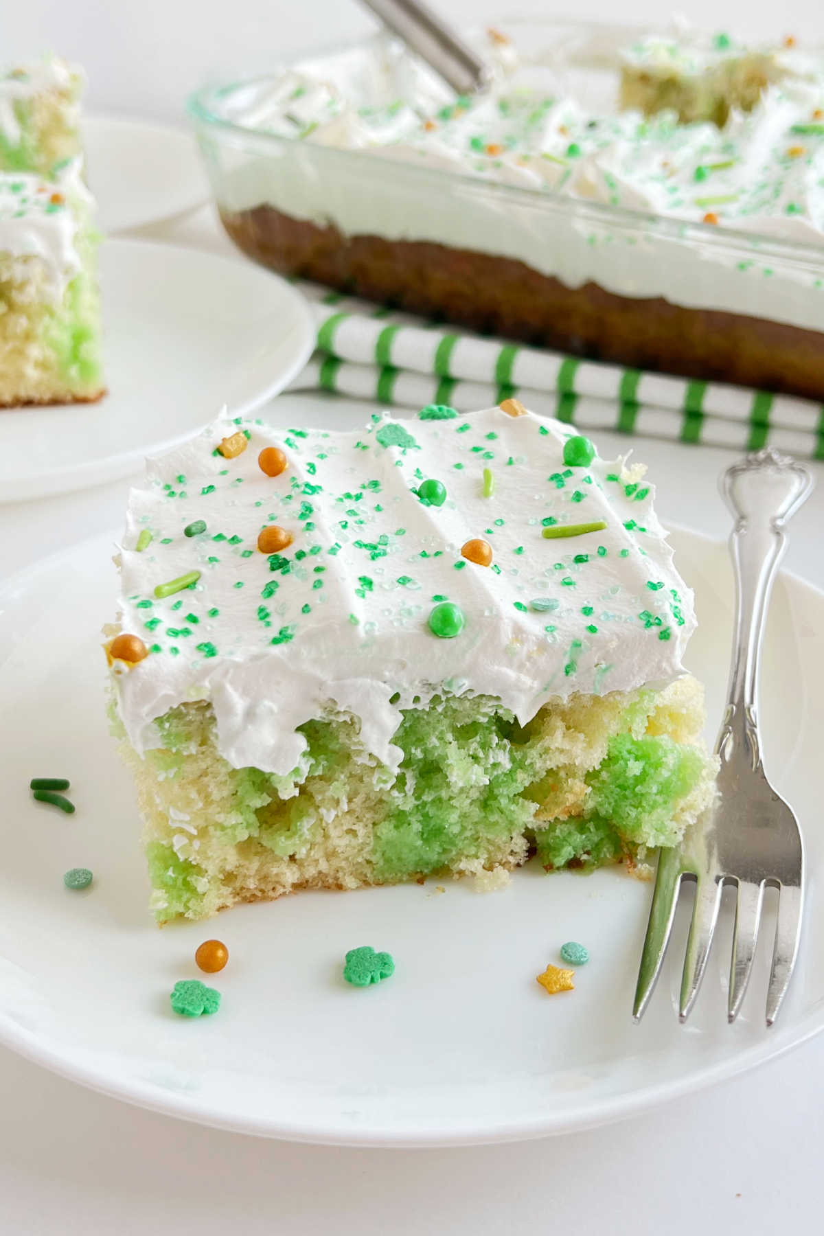 lime jello poke cake with cool whip frosting and St. Patrick's Day sprinkles