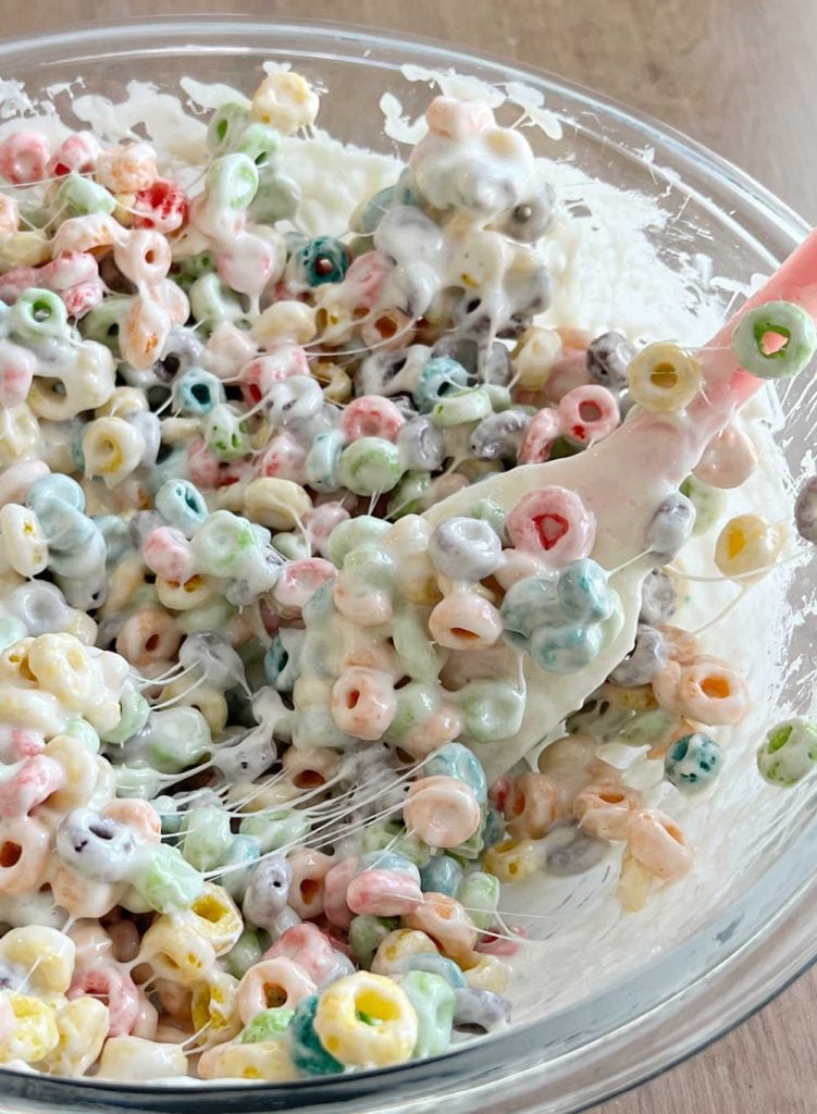 stir froot loops into melted marshmallows with rubber spatula