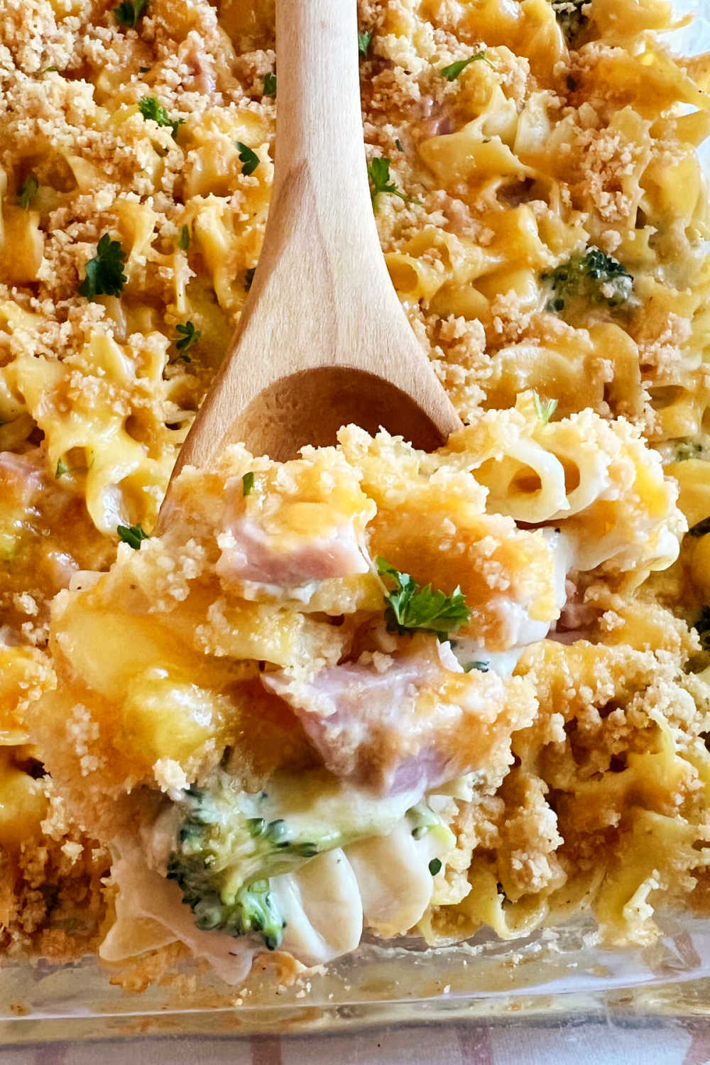 leftover ham casserole with egg noodles and broccoli in creamy sauce on wooden spoon