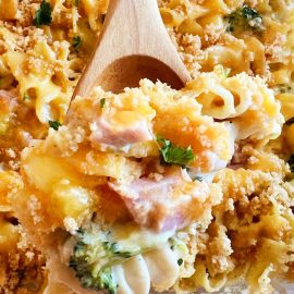 leftover ham casserole with broccoli, cheddar cheese and butter cracker crumbs on a wooden spoon
