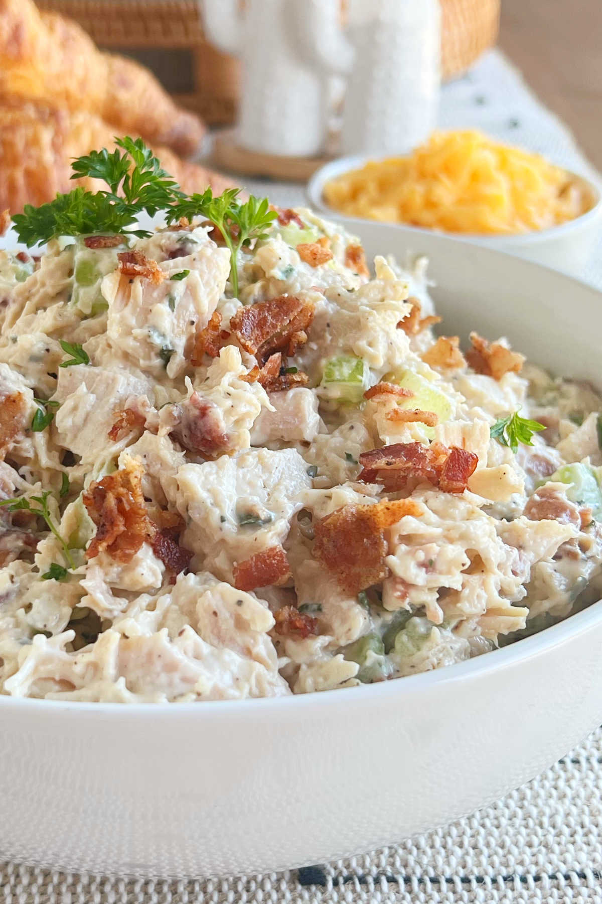 bowl of ranch chicken salad with bacon next to cheese and croissants