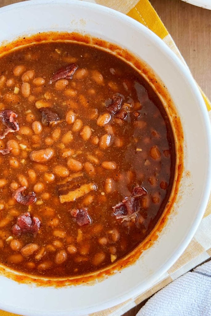 closeup of baked beans in casserole dish with bacon and brown sugar