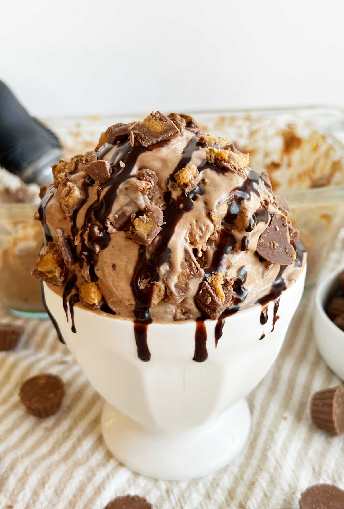 bowl of homemade chocolate peanut butter ice cream with chocolate syrup and mini Reese's cups