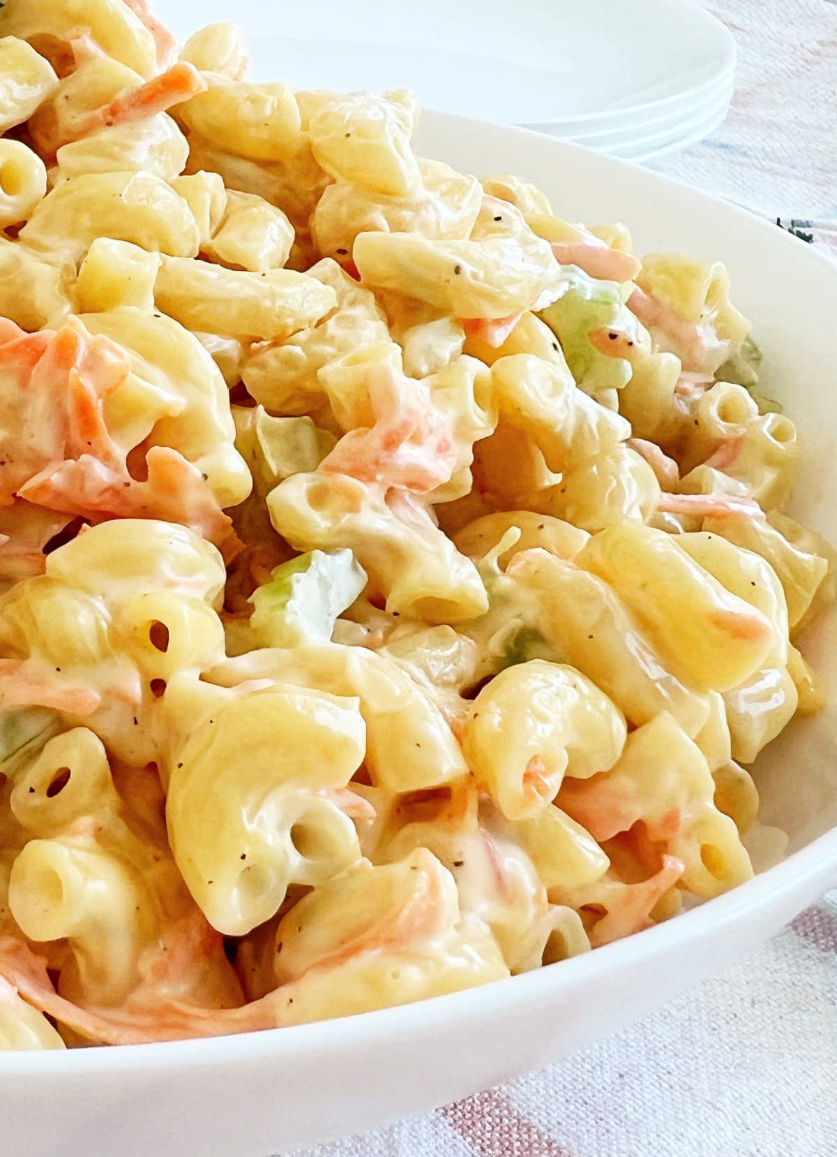 side view of Hawaiian macaroni salad with carrots and celery in bowl on the table.