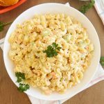Hawaiian macaroni salad with carrots and celery and parsley in white bowl