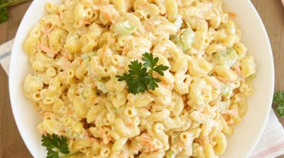 Hawaiian macaroni salad with carrots and celery and parsley in white bowl