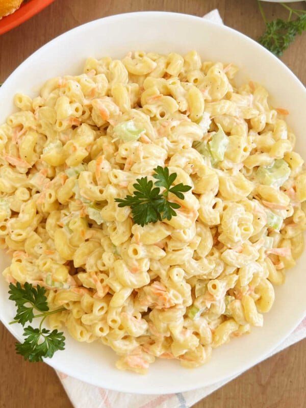 Hawaiian macaroni salad with carrots and celery and parsley in white bowl