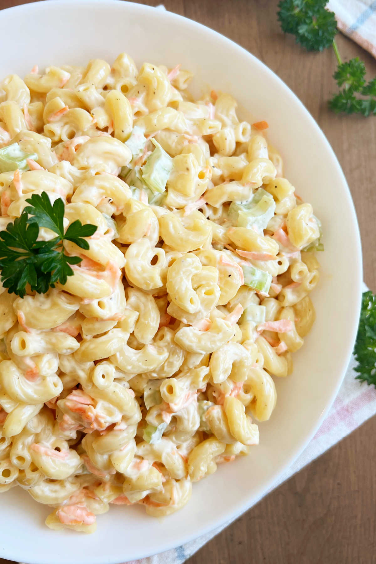 bowl of mac salad with creamy dressing and fresh parsley on the table.