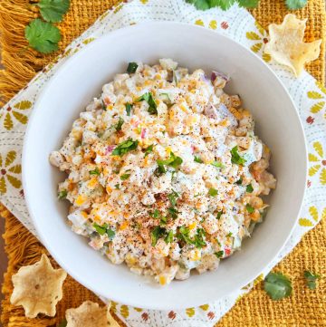 Mexican street corn salad (elote salad) topped with cotija cheese and cilantro in a white serving bowl