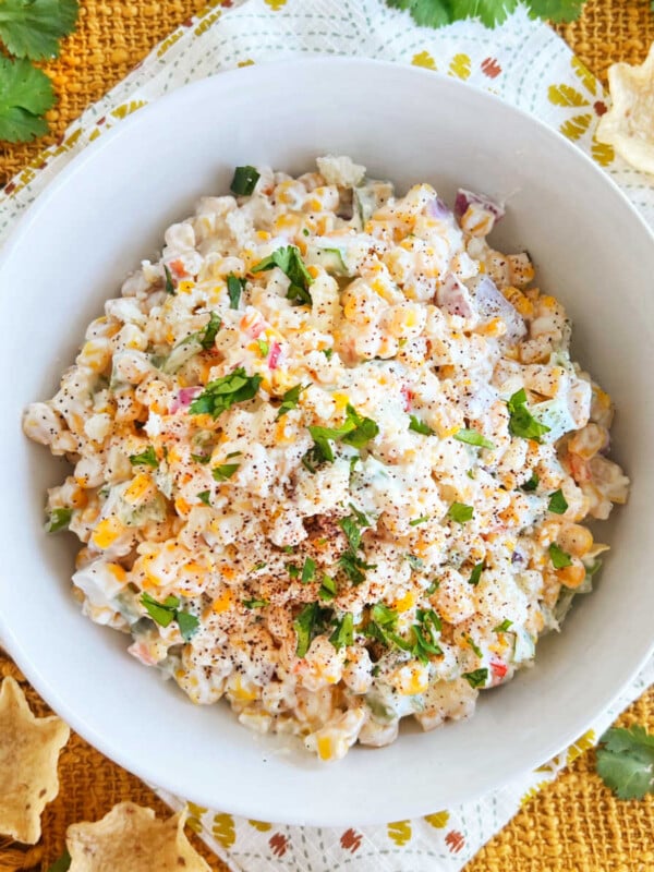 Mexican street corn salad (elote salad) topped with cotija cheese and cilantro in a white serving bowl