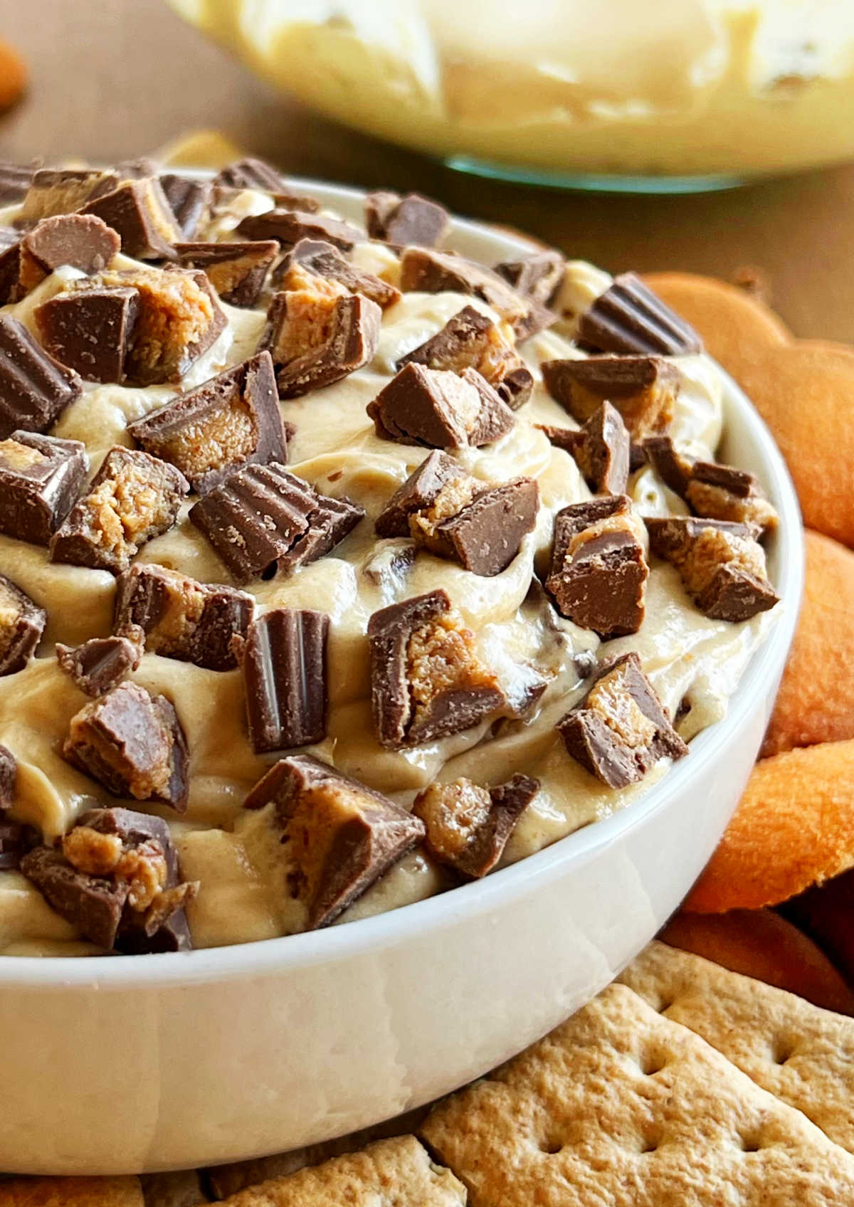 bowl of peanut butter cheesecake dip with mini Reese's peanut butter cups on top