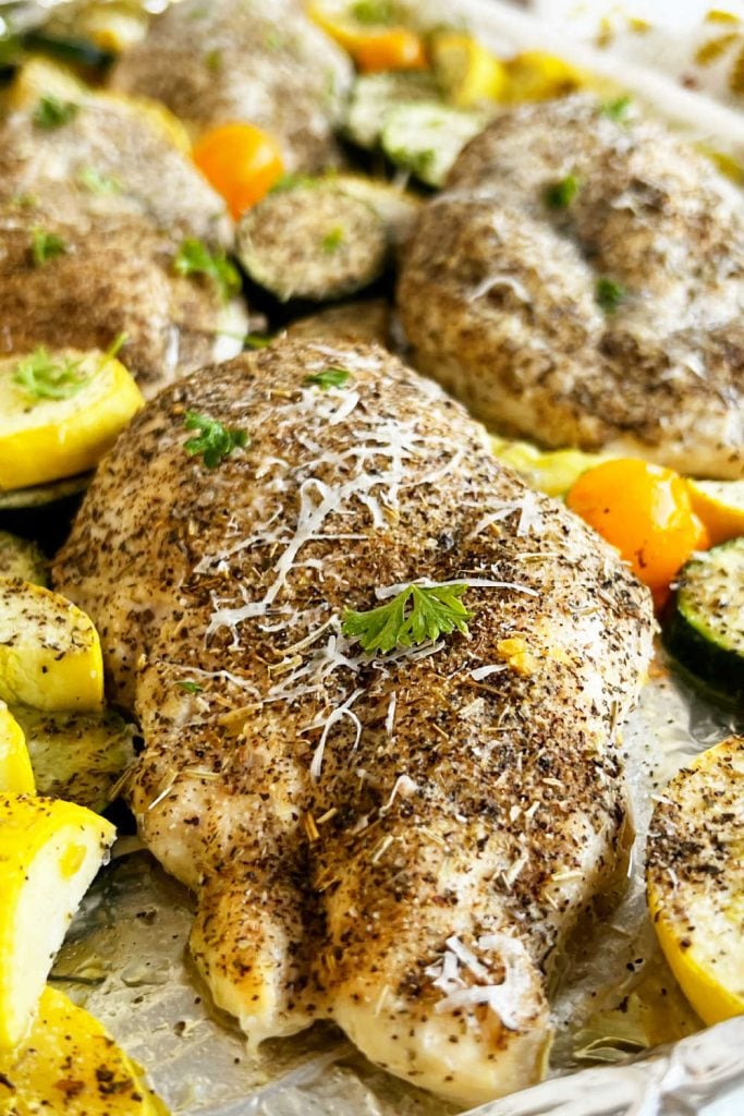 seasoned baked chicken breast with zucchini and yellow squash on sheet pan