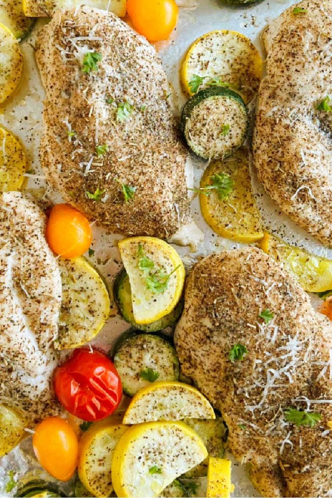 baked chicken and zucchini with yellow squash and grape tomatoes on sheet pan.