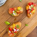 bruschetta toasts with fresh tomatoes and basil and feta cheese on wooden board