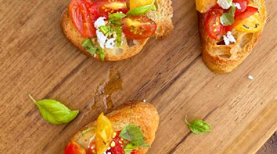bruschetta toasts with fresh tomatoes and basil and feta cheese on wooden board