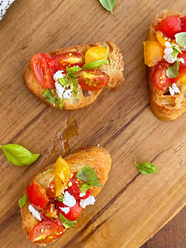 bruschetta toasts with fresh tomatoes and basil and feta cheese on wooden board