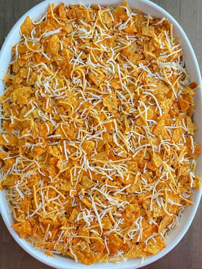 chicken dorito casserole topped with Doritos and cheddar cheese in baking dish